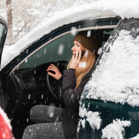 Autofahren im Winter, Frau sitzt in verschneitem Auto