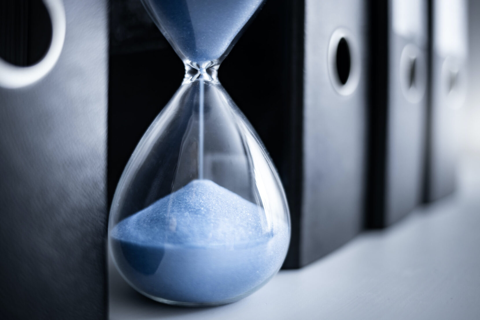 Eine Sanduhr zwischen Ordnern als Symbol für Verjährung im Strafrecht