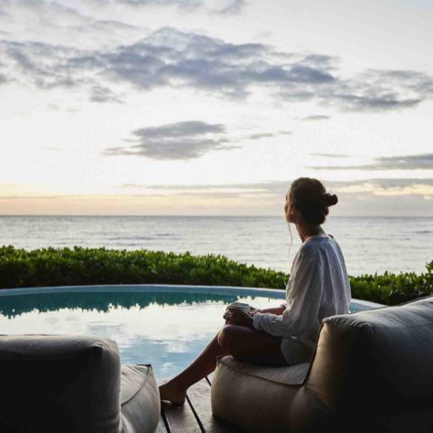 Eine Frau sitzt im Sonnenuntergang am Pool