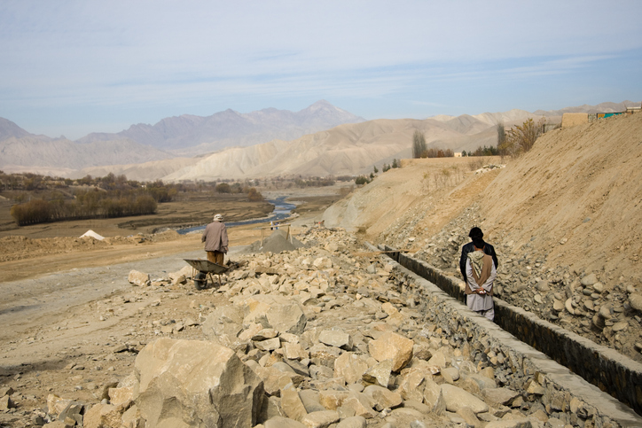 Zwei Menschen laufen über Trümmer am Straßenrand in Afghanistan, ein Land mit Tempolimit