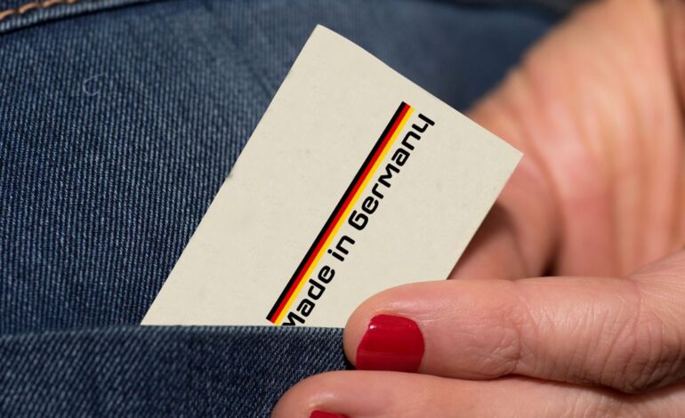 Hand mit lackierten Nägeln zieht eine Karte mit Made in Germany aus einer Hosentasche