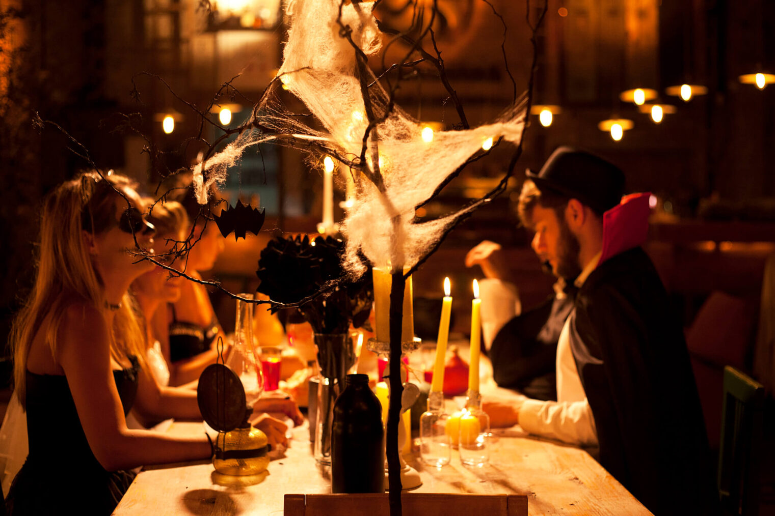 Freundesgruppe in Kostümen feiert Halloween-Veranstaltung an dekoriertem Tisch