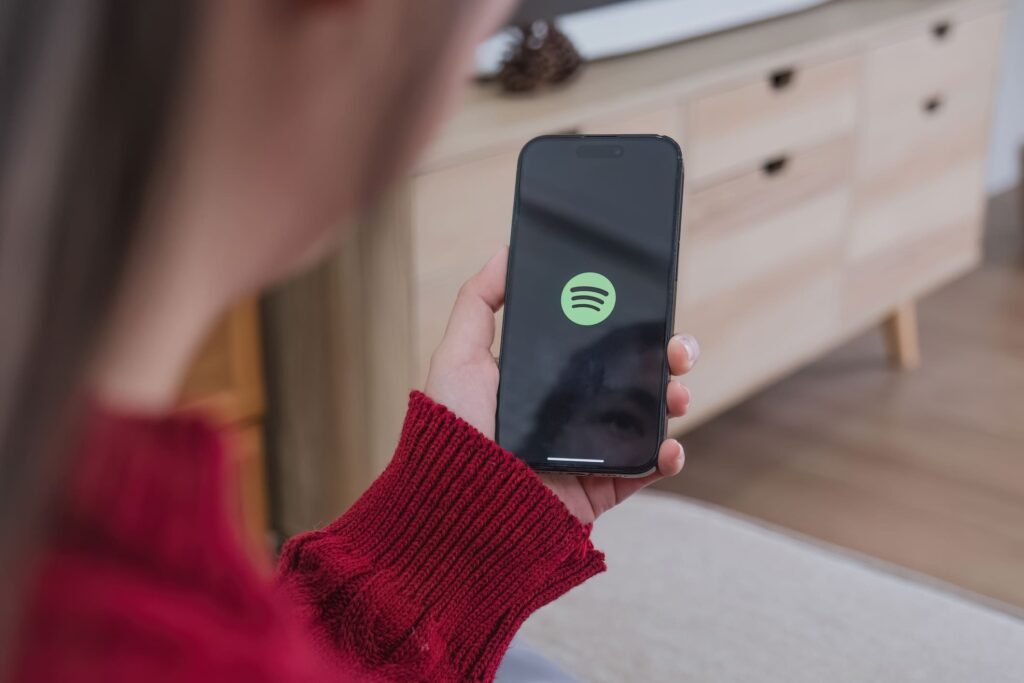 Eine Frau hält ein Smartphone in der Hand, das das Spotify-Symbol anzeigt.
