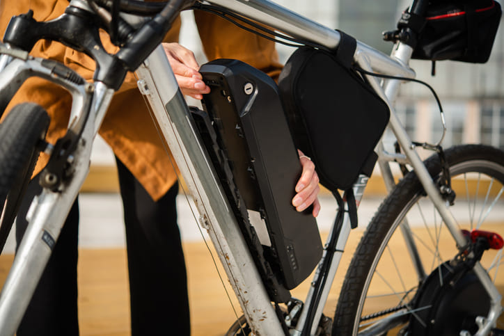 Jemand nimmt die Batterie eines E-Bikes ab.