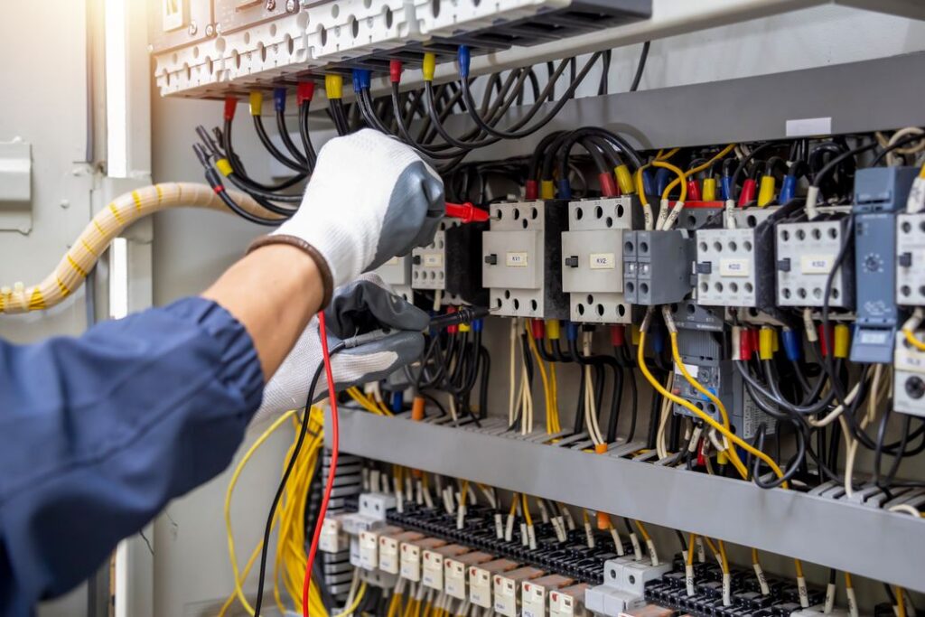 Eine behandschuhte Hand, die an einem Stromkasten arbeitet.